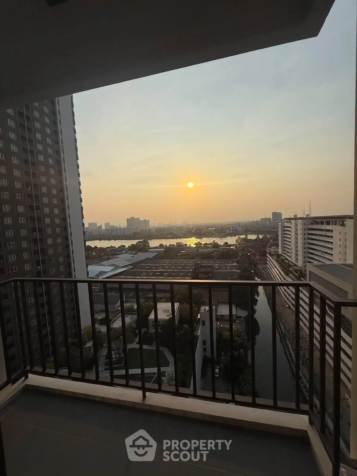 Stunning sunset view from a high-rise balcony overlooking the city skyline and river.