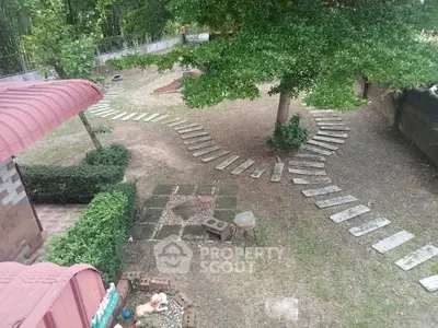 Charming backyard garden with a creative stepping stone path, surrounded by lush greenery and mature trees, offering a serene outdoor retreat.