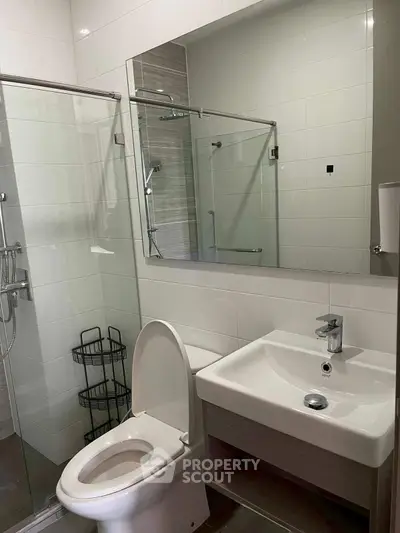 Modern bathroom with glass shower and sleek fixtures in contemporary apartment.