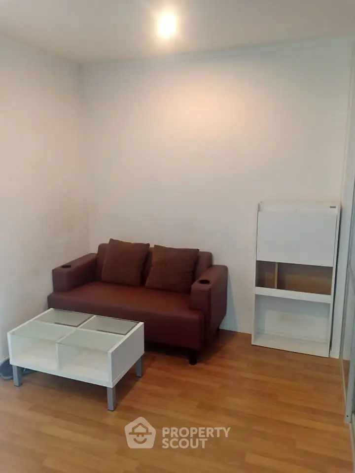 Cozy living room with brown sofa, white coffee table, and wooden flooring.
