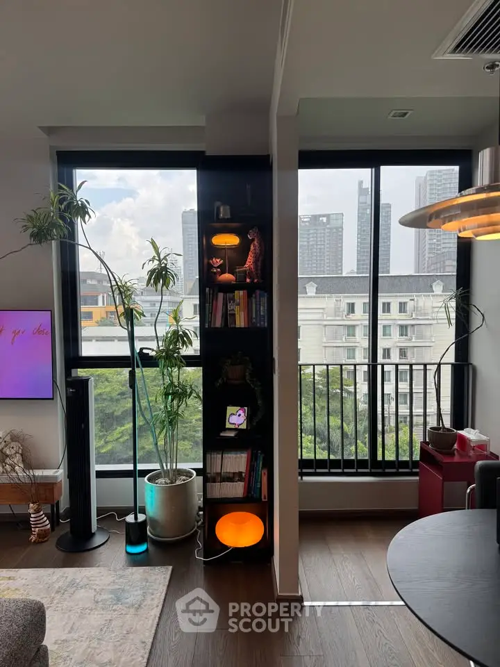 Modern living room with large windows and city view, featuring stylish decor and indoor plants.