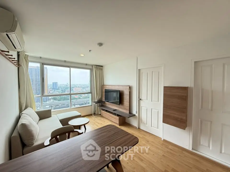 Modern living room with city view, featuring sleek furniture and large windows for natural light.