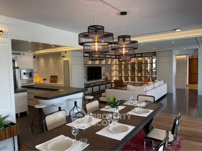 Luxurious open-plan living room with modern kitchen and elegant dining area, featuring stylish lighting and decor.
