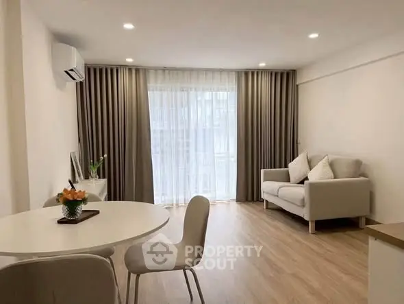 Modern living room with elegant decor and natural light, featuring a cozy sofa and dining area.
