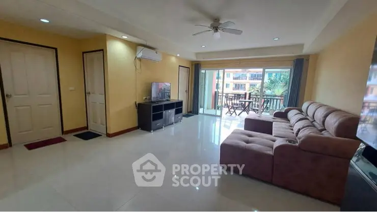 Spacious living room with large sofa and balcony access in modern apartment