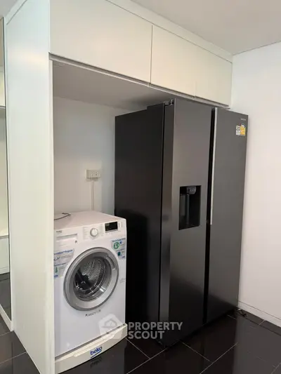 Modern kitchen with sleek black fridge and washing machine