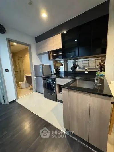 Modern kitchen with sleek cabinetry and integrated appliances next to a compact bathroom.