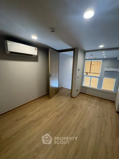 Modern bedroom with wooden flooring and air conditioning in a stylish apartment.