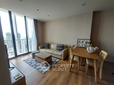 Modern living room with city view, stylish furniture, and wooden flooring in high-rise apartment.