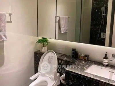 Luxurious modern bathroom with sleek black marble countertop and elegant fixtures.