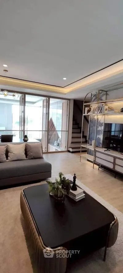 Luxurious modern living room with elegant decor and large windows offering natural light.