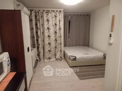 Cozy bedroom with bed, air conditioner, and microwave in a compact layout.