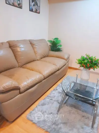Cozy living room with plush leather sofa and glass coffee table on a soft rug.