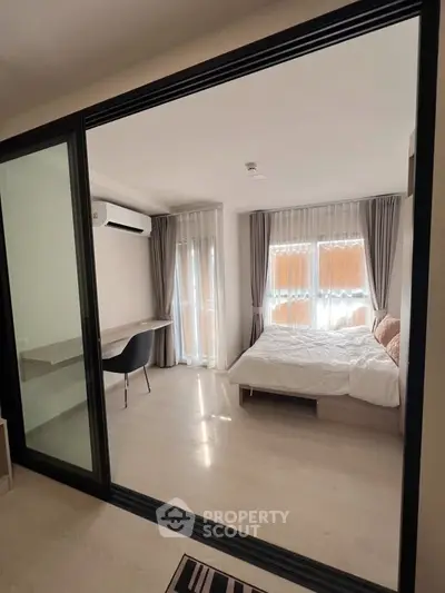 Modern bedroom with large windows and sleek design, featuring a cozy bed and workspace.