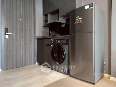 Modern kitchen with sleek appliances including fridge and washing machine in stylish apartment.