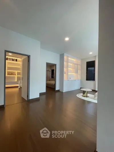Spacious modern living room with elegant wooden flooring and built-in shelving, perfect for stylish urban living.