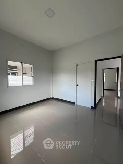 Spacious empty room with glossy tiled floor and large windows in modern apartment.