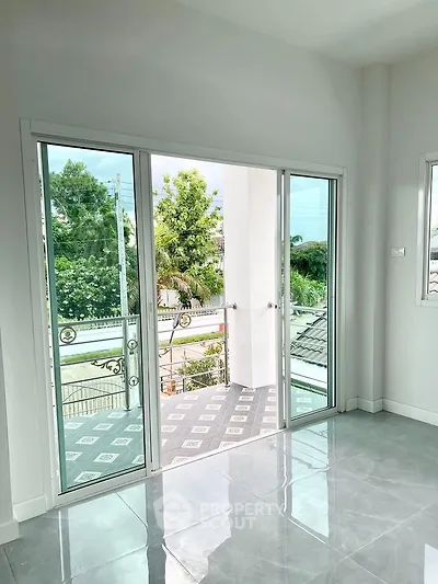 Bright room with large sliding glass doors opening to a balcony with lush green views.