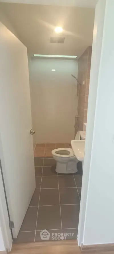 Modern bathroom with sleek design and neutral tiles, featuring a shower and toilet.