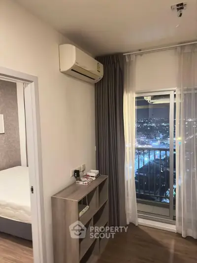 Modern bedroom with air conditioning and city view balcony at night.