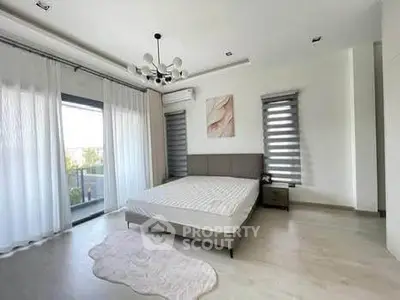 Spacious bedroom with modern decor and large windows offering natural light.