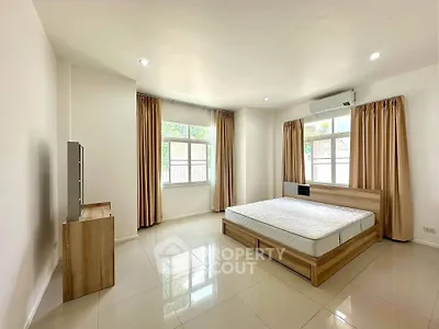 Spacious bedroom with natural light and modern furnishings in a serene setting.