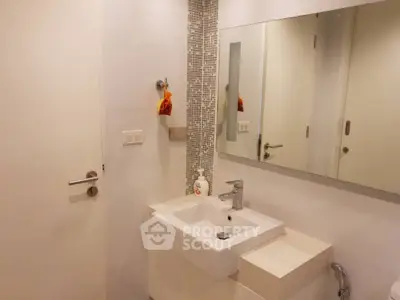 Modern bathroom with sleek sink and large mirror in a minimalist design.