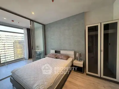 Modern bedroom with large windows and city view, featuring sleek furniture and stylish decor.