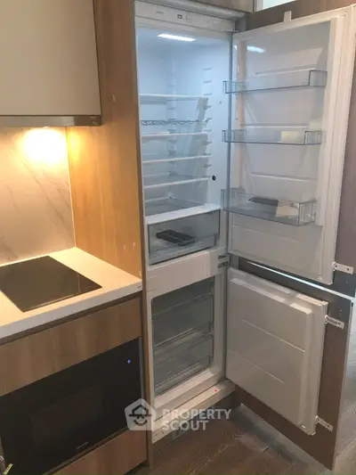Modern kitchen with built-in fridge and sleek appliances in stylish apartment.
