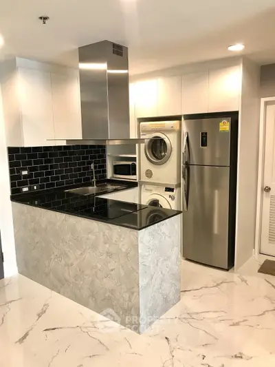 Modern kitchen with sleek appliances and stylish black backsplash in a contemporary apartment.