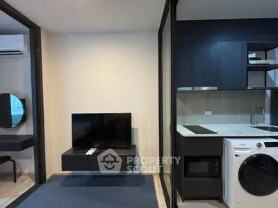 Modern apartment interior with sleek kitchen and living area featuring a wall-mounted TV and washer-dryer combo.