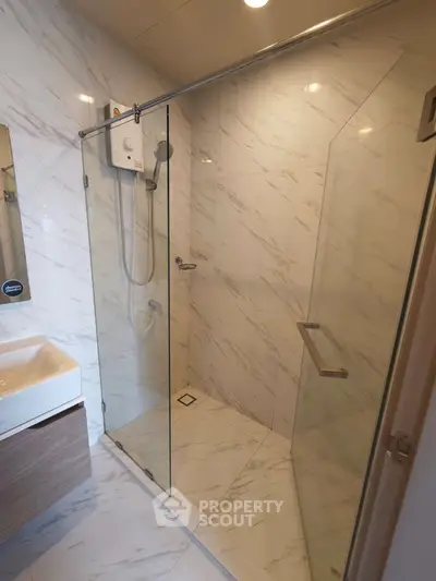 Modern bathroom with glass shower enclosure and sleek marble tiles