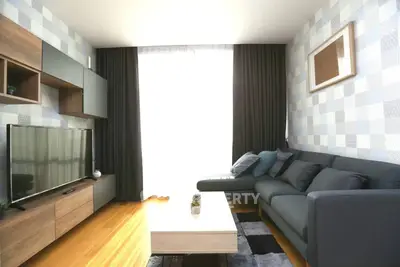 Modern living room with stylish furniture and large TV, featuring elegant decor and natural light.