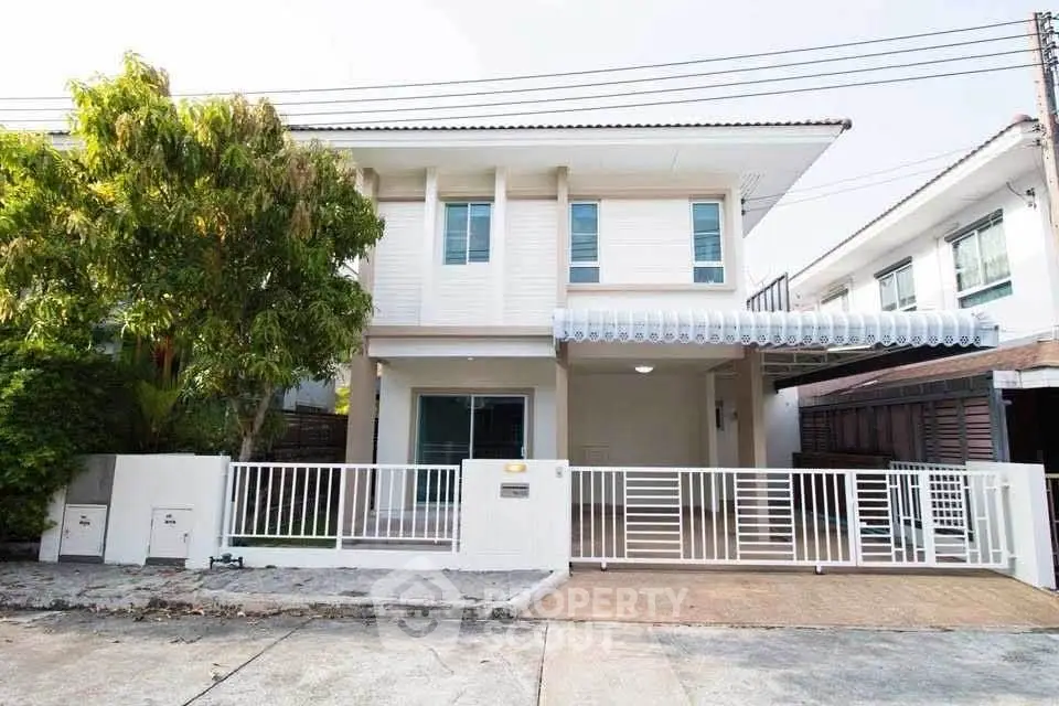 Charming two-story house with modern facade and gated driveway in a serene neighborhood.