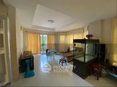 Spacious living room with large windows and natural light, featuring a fish tank and modern decor.