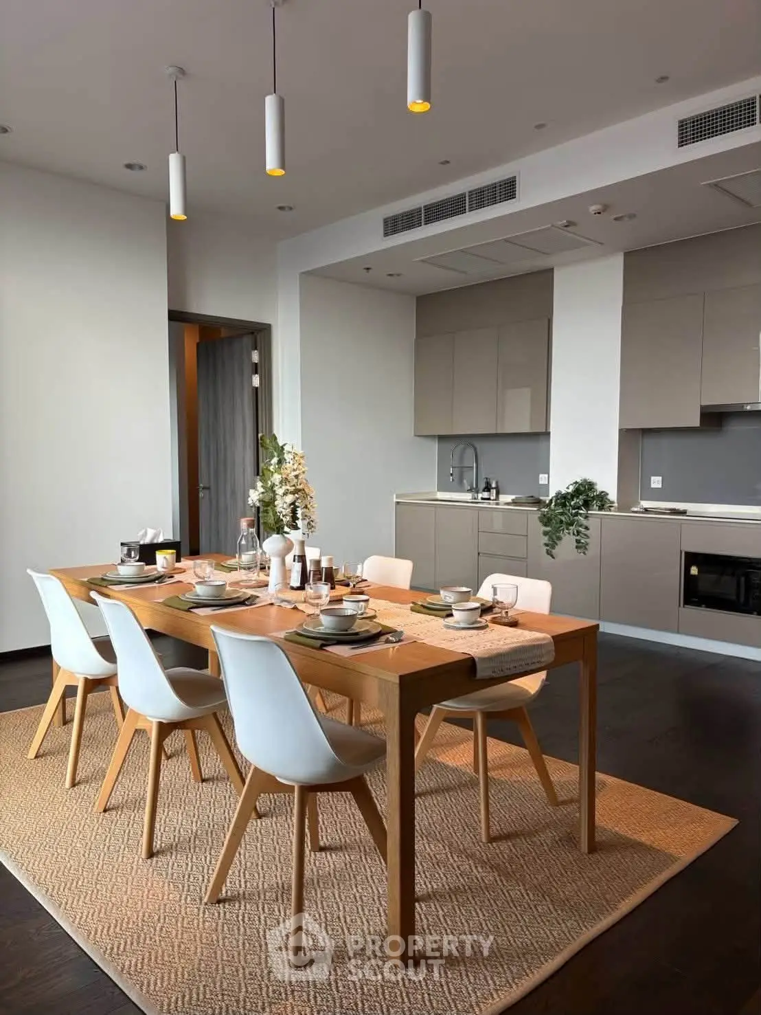 Modern dining area with sleek kitchen, wooden table, and elegant decor in a stylish apartment.