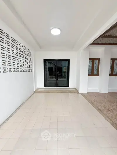 Spacious covered patio area with tiled flooring and modern sliding glass doors, perfect for outdoor relaxation.