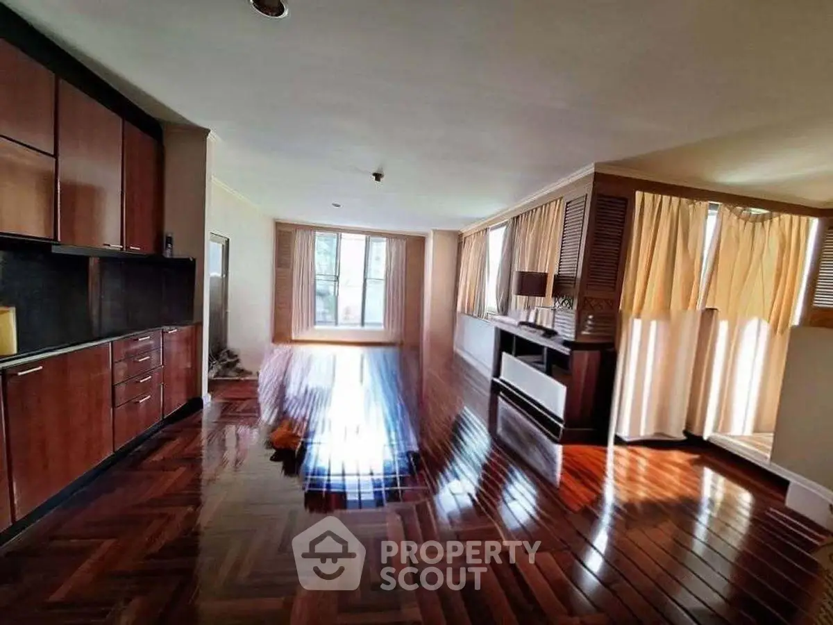 Spacious living room with polished wooden floors and ample natural light.