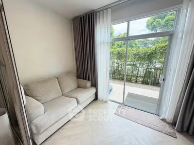Cozy living room with large window and garden view, featuring a comfortable sofa and elegant curtains.