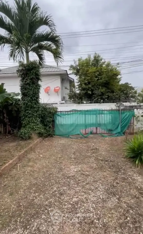 Charming suburban property with lush greenery and secure gated entrance, perfect for privacy and tranquility.