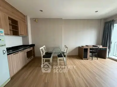 Modern open-layout kitchen and dining area with wooden flooring and natural light.