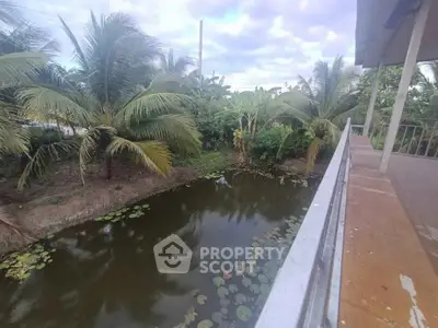Scenic view from balcony overlooking lush garden and tranquil pond with lily pads.