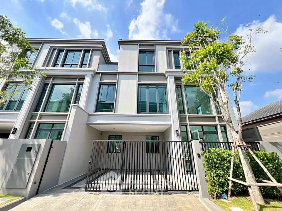 Modern townhouse exterior with sleek design and gated entrance under a clear blue sky.