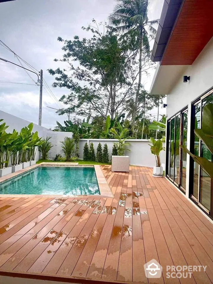 Luxurious modern home with private pool and elegant wooden deck surrounded by lush greenery.