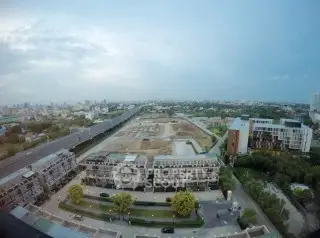 Stunning aerial view of modern residential complex with lush greenery and cityscape backdrop.