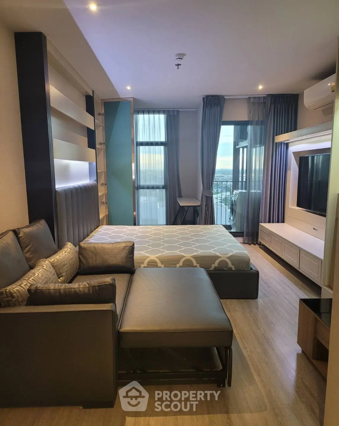 Modern studio apartment with stylish decor and city view, featuring a cozy living area and sleek furnishings.