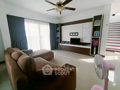 Spacious living room with modern decor, large sofa, and ceiling fan, perfect for relaxation and entertainment.