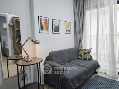 Cozy living room with modern decor and natural light, featuring a stylish sofa and artistic wall frames.