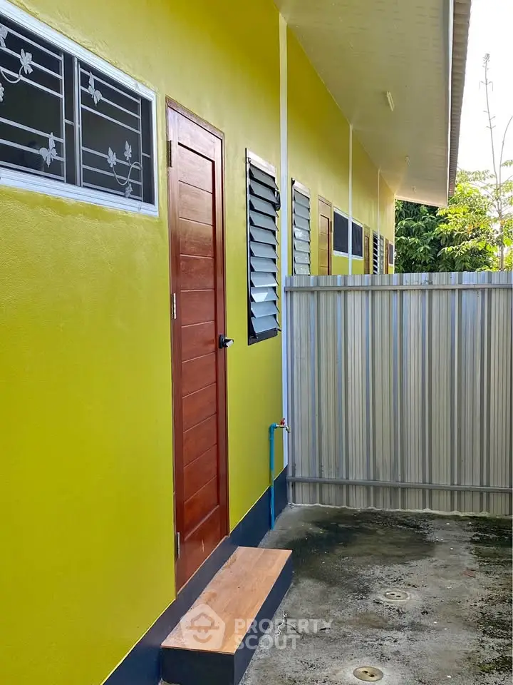 Vibrant yellow exterior of a modern building with secure fencing and stylish windows.
