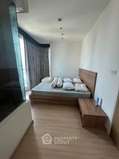Spacious bedroom with modern wooden furniture and large windows for natural light.
